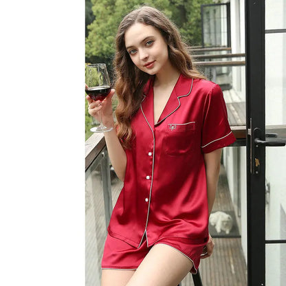 Woman in red satin pajama set holding a glass of wine on a balcony.
