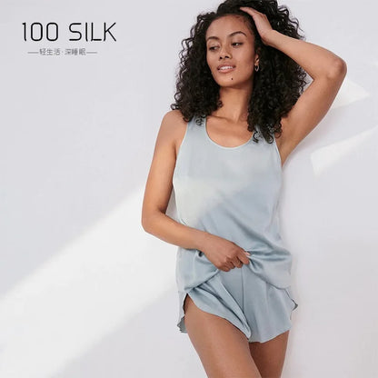 Woman wearing a light blue silk dress with '100 SILK' branding on a white background