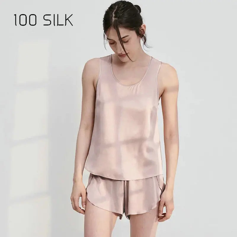 Woman wearing a pink silk tank top and shorts set on a white background with '100 SILK' text.