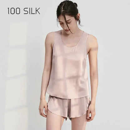 Woman wearing a pink silk tank top and shorts set on a white background with '100 SILK' text.