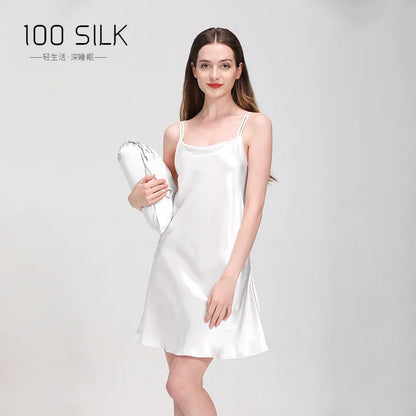 Woman wearing a white silk dress holding a white silk pillow on a gray background with '100 SILK' branding.