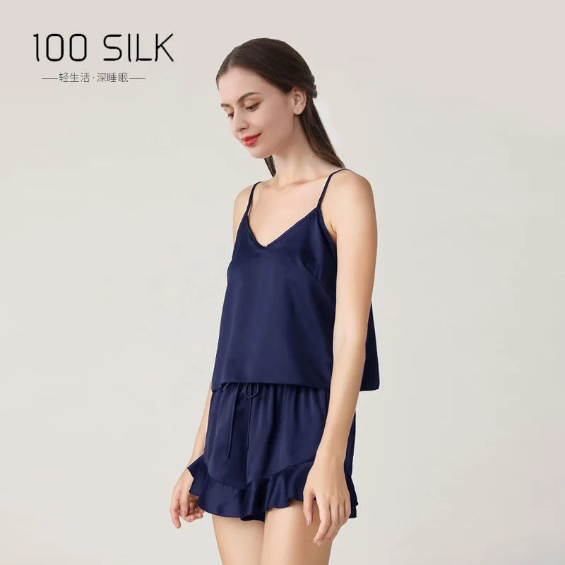 Woman wearing a navy blue silk nightgown with '100 SILK' branding on a light gray background.