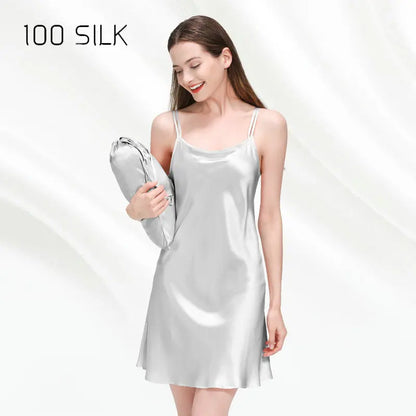 Woman wearing a silver satin slip dress holding a matching bag on a white background with '100 SILK' text.