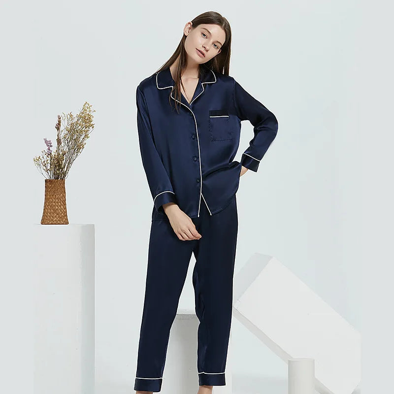 Woman wearing navy blue pajamas with white piping on a white background