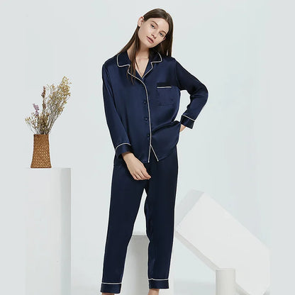 Woman wearing navy blue pajamas with white piping on a white background