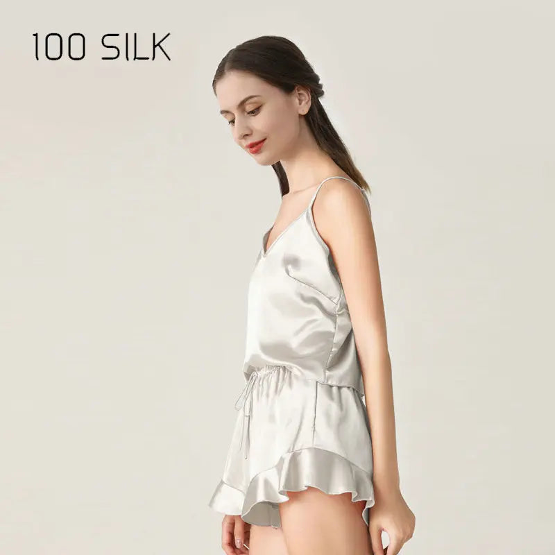 Woman wearing a silver silk dress with '100 SILK' branding on a light background