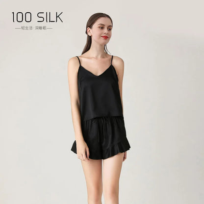 Woman wearing a black silk slip dress with '100 SILK' branding on a light gray background