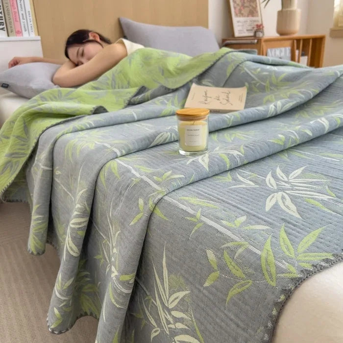 Person lying on a bed with a green and gray patterned blanket, candle, and books in the background.