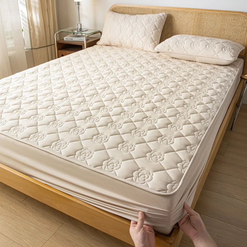 Person adjusting a mattress cover on a bed in a bedroom setting.