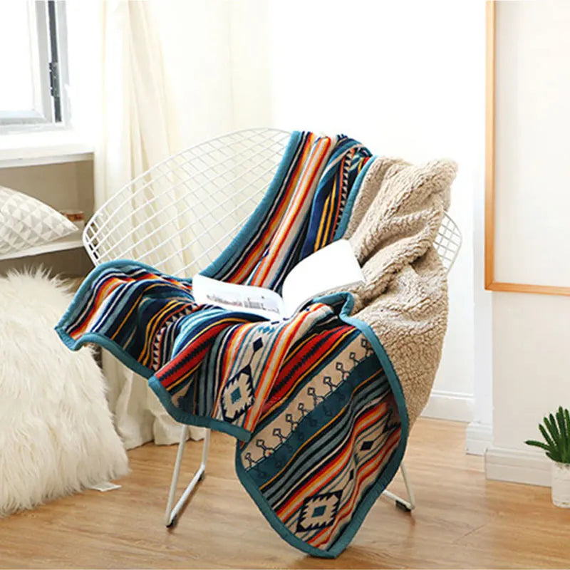 Colorful patterned blanket draped over a chair in a room with light decor.