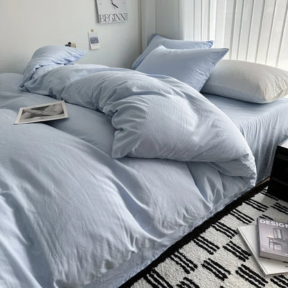 Light blue bedding set on a bed with a white wall and decorative items in the background.