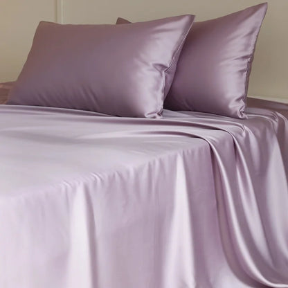 Purple satin sheet set with matching pillows on a bed.