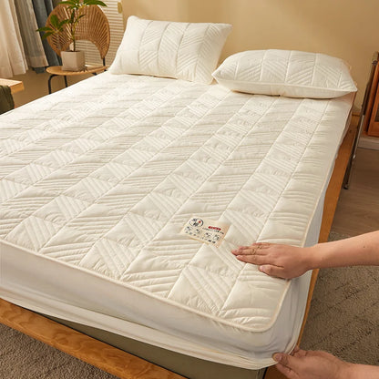 White quilted mattress cover being placed on a bed in a room setting.
