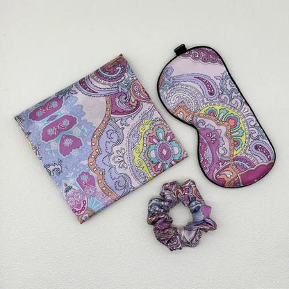 Set of paisley-patterned pouch, eye mask, and scrunchie on a light gray background
