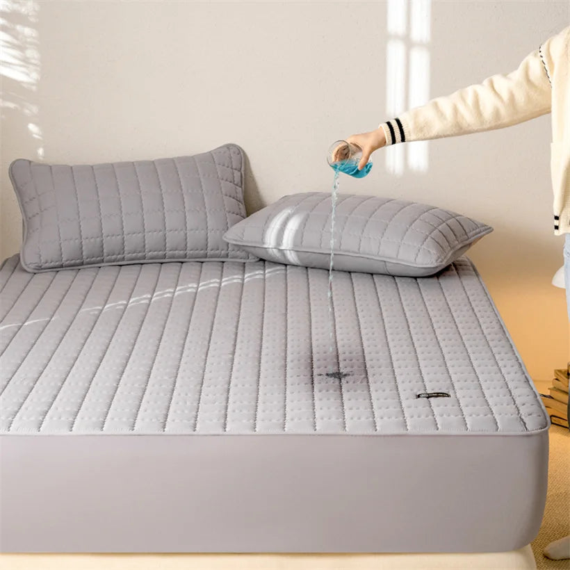 Gray quilted mattress cover on a bed with a person pouring water onto it.