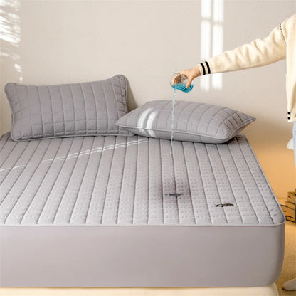 Gray quilted mattress cover on a bed with a person pouring water onto it.