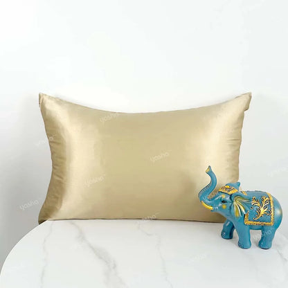 Gold satin pillow and blue elephant figurine on a white surface